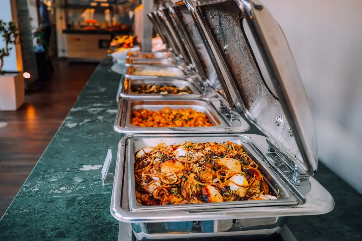 Buffet com cubas de comida quente e pratos frios