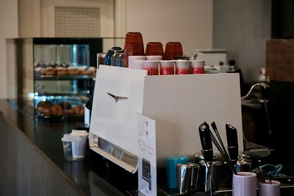 Balcão de cafeteria com máquina de espresso e doces na vitrine